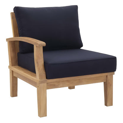 Natural wood patio armchair with navy cushions; thick seat and tall back, curved armrests.