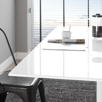Glossy white rectangular table with chrome legs in a bright modern room; mug, magazine, spoon & French press on top.
