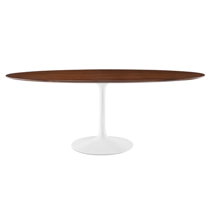 Oval walnut wood dining table on a white tulip pedestal base, mid-century modern design.