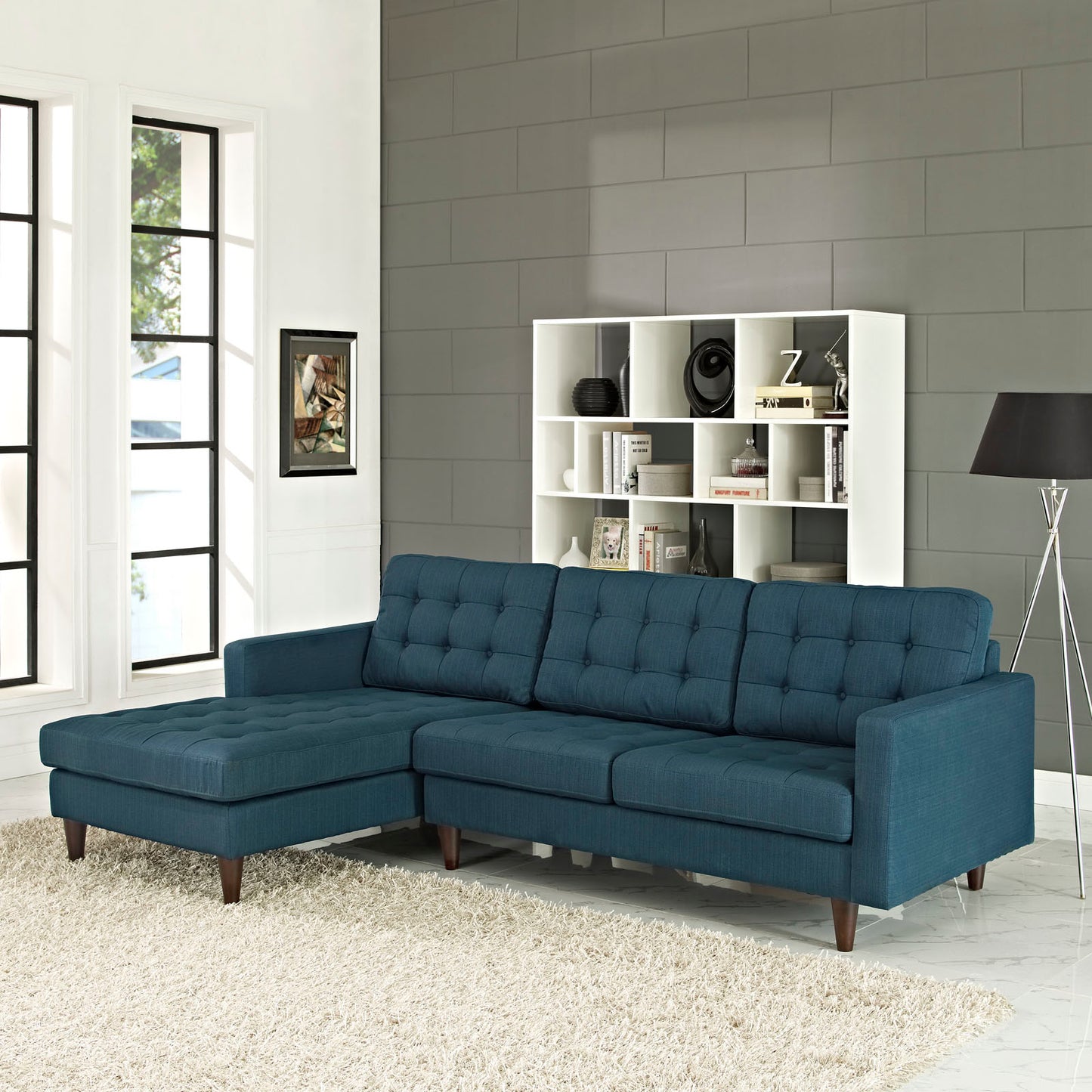 Azure blue fabric sectional sofa with tufted back and chaise on left, mid-century wood legs.