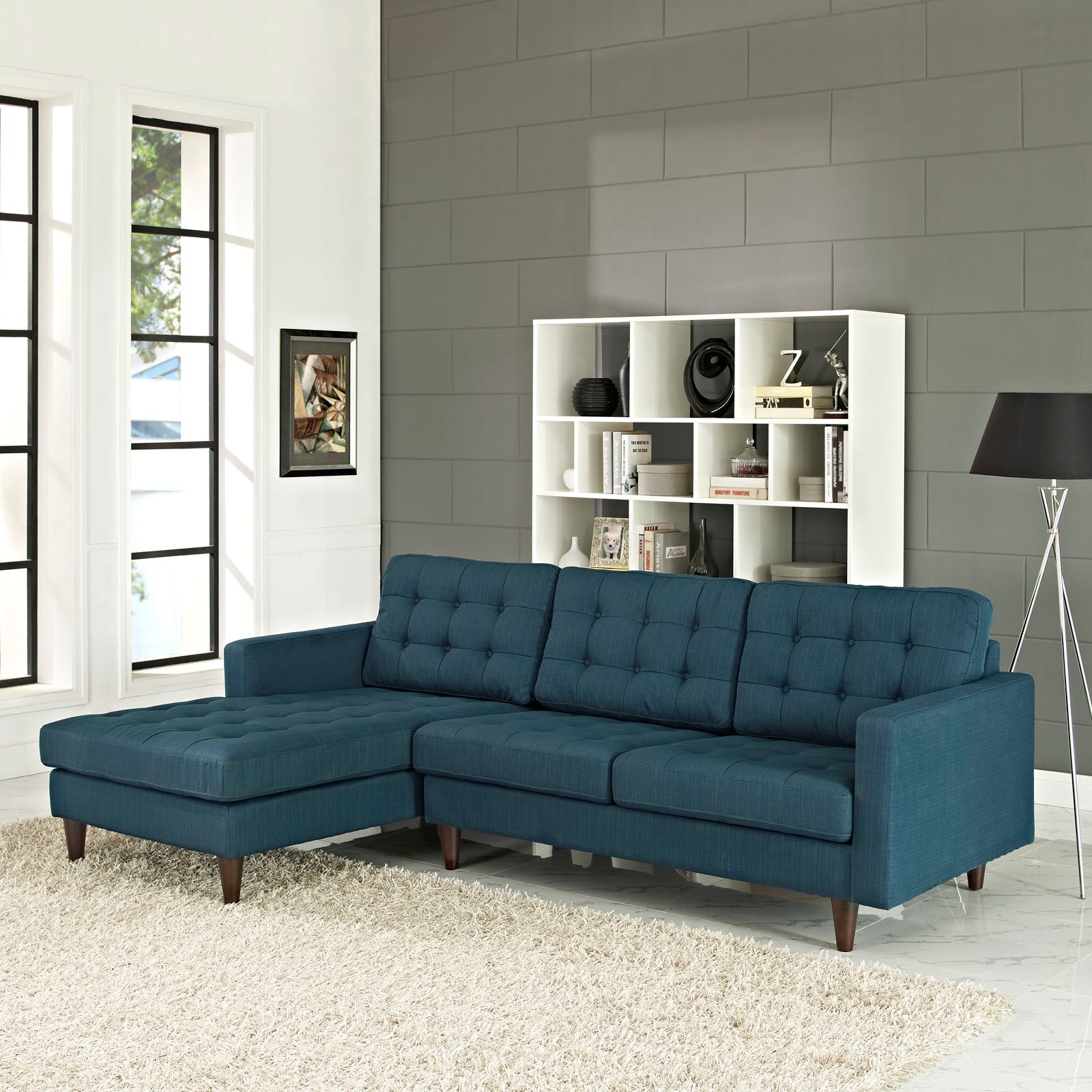 Azure blue fabric sectional sofa with tufted back and chaise on left, mid-century wood legs.