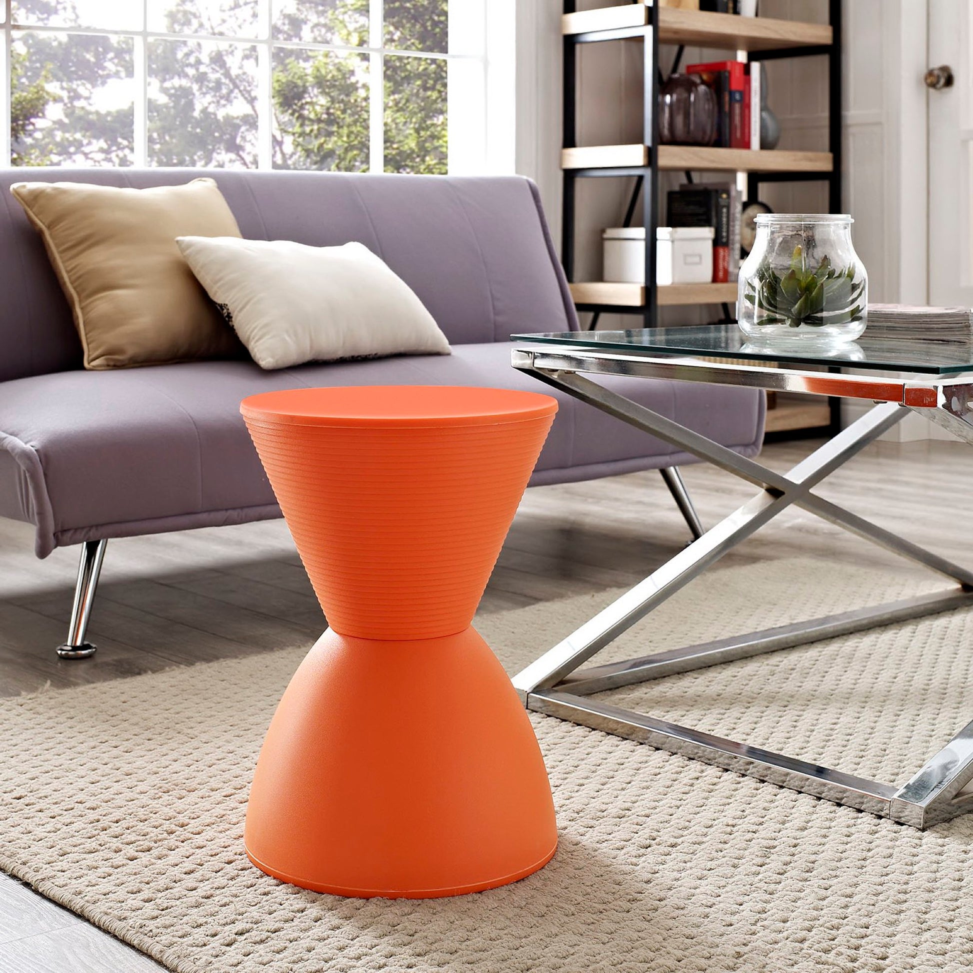 Bright orange hourglass-shaped plastic stool with a ribbed top, used as a side table in a contemporary living room.