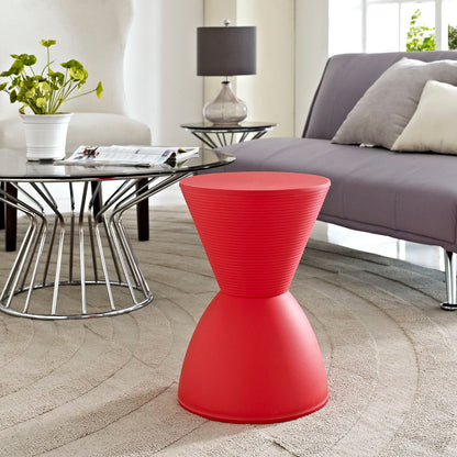 Red ribbed conical plastic stool in a modern living room with glass coffee table and gray sofa.
