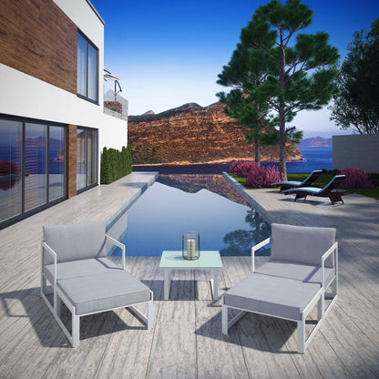 Poolside outdoor lounge set with light gray cushions and white metal frames, glass-top side table on a wooden deck.