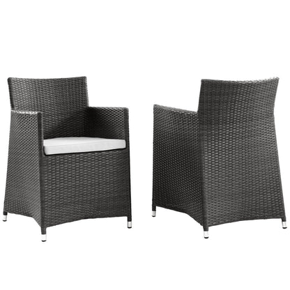 Pair of dark brown wicker outdoor armchairs with white cushions for patio use.