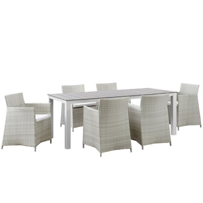Outdoor dining set: rectangular gray slatted table with white frame, surrounded by light gray wicker chairs with white cushions.