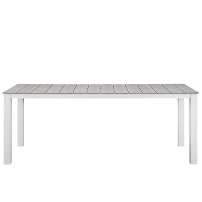 Long rectangular outdoor table with gray slatted wooden top and white legs.