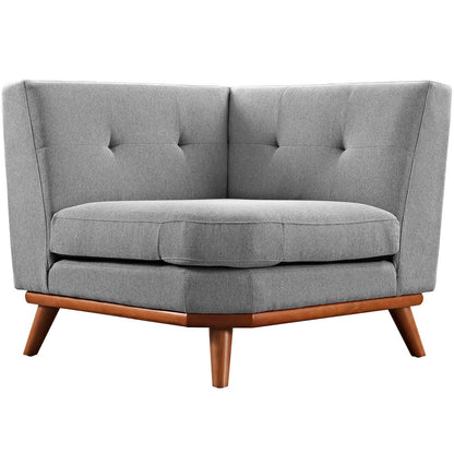 Gray fabric tufted corner chair with curved back and tapered wooden legs.