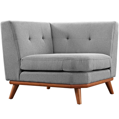 Grey fabric corner chair with tufted back and angled wooden legs.