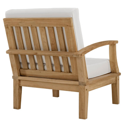 Natural wood outdoor lounge chair with white cushions, slatted back and curved armrests.