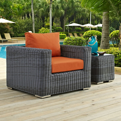 Gray fabric outdoor armchair with orange cushions and a matching side table beside a pool.