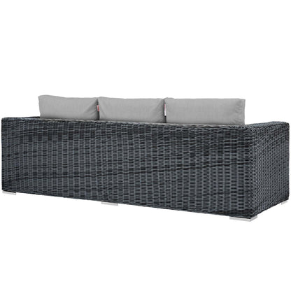 Dark gray woven rattan outdoor sofa with light gray cushions, modern low-profile patio seating.