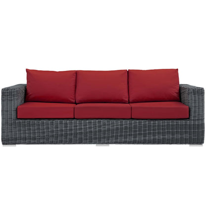 Grey wicker outdoor sofa with red seat cushions & red back cushions, three-seater.