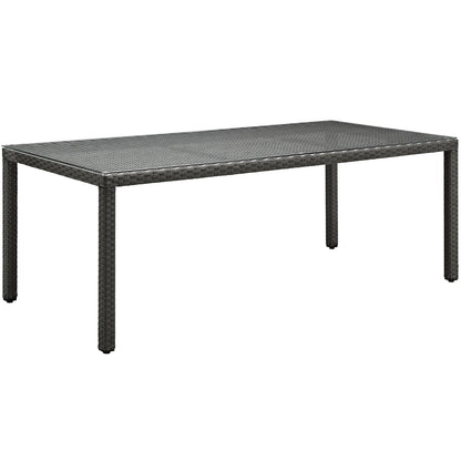 Rectangular dark brown wicker outdoor dining table with woven top and four sturdy legs.