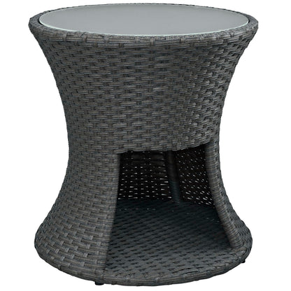 Round glass-top outdoor table in dark charcoal wicker with curved hourglass base and lower shelf.