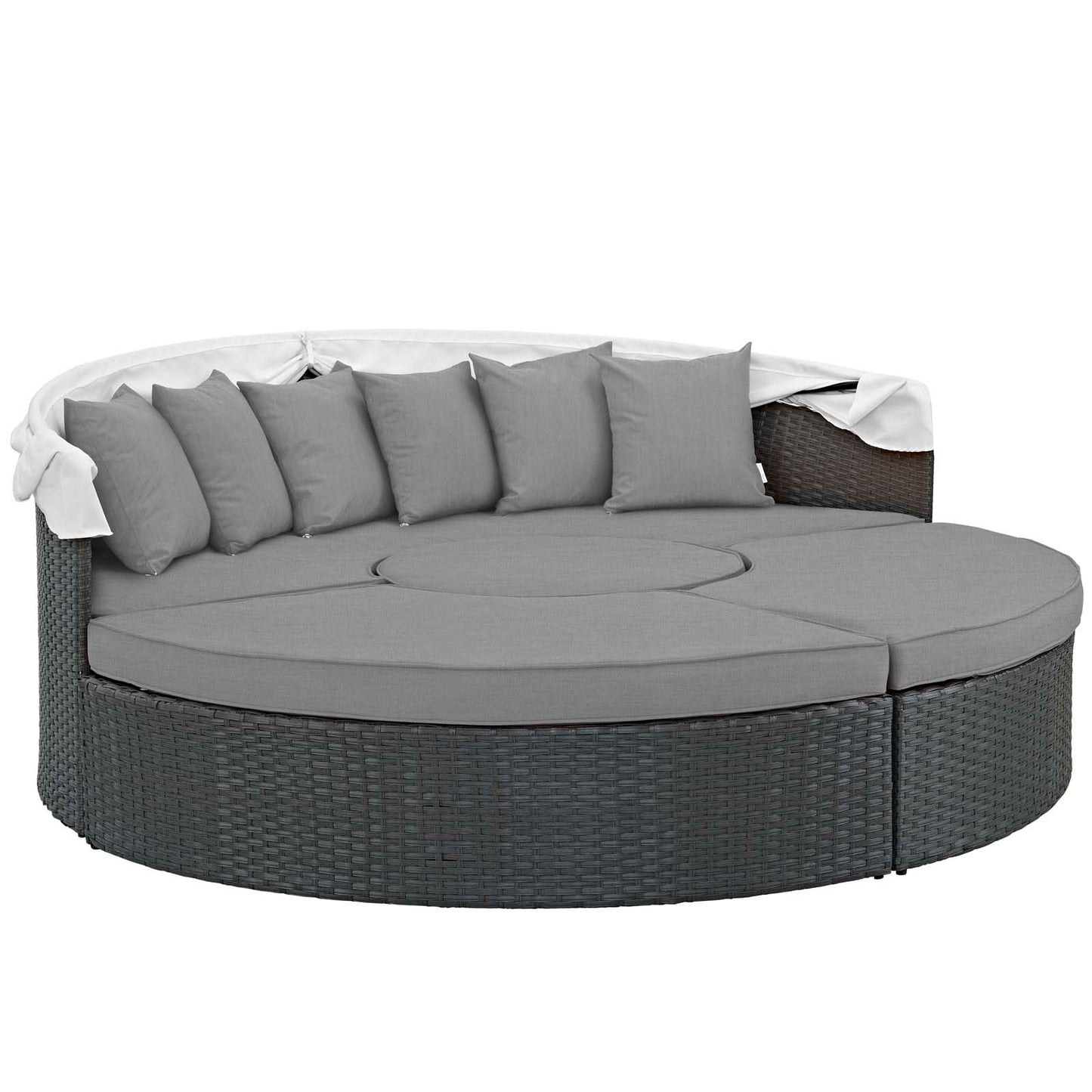 Round gray wicker outdoor daybed with curved cushions and multiple gray pillows; white throw blanket draped over edge.