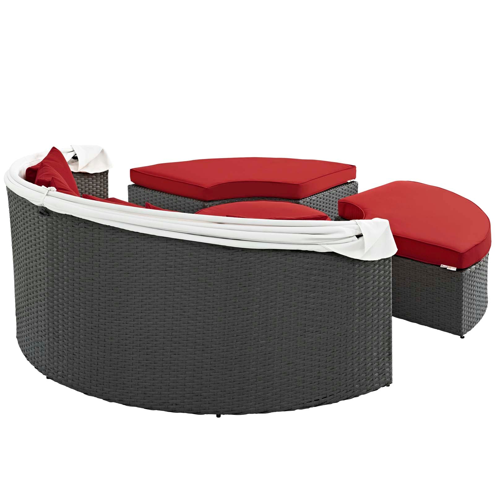 Curved gray wicker outdoor daybed with red cushions and a matching ottoman, white fabric accents.