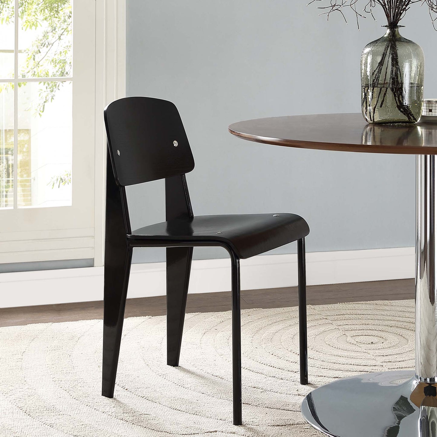 Black padded dining side chair with faux-leather seat and back, slim metal legs; modern minimalist style.