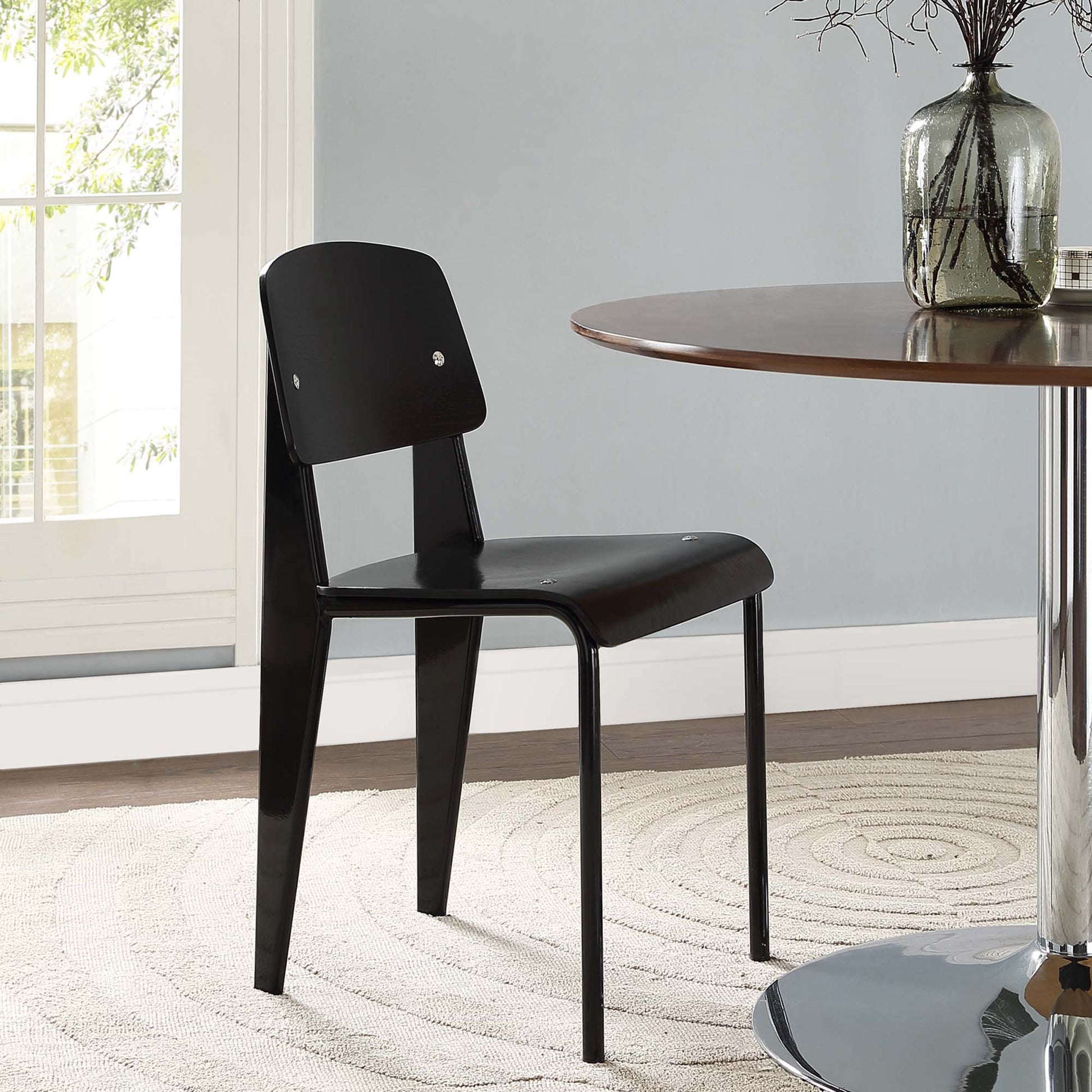 Black padded dining side chair with faux-leather seat and back, slim metal legs; modern minimalist style.