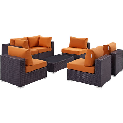 Dark wicker outdoor modular sectional with orange cushions & matching coffee table.