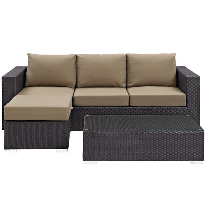 Dark brown outdoor wicker sectional with beige cushions and glass-top coffee table; chaise on left.