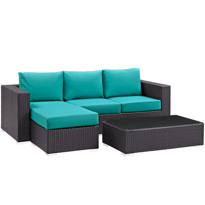 Dark brown wicker outdoor sectional with teal cushions and a matching rectangular coffee table.