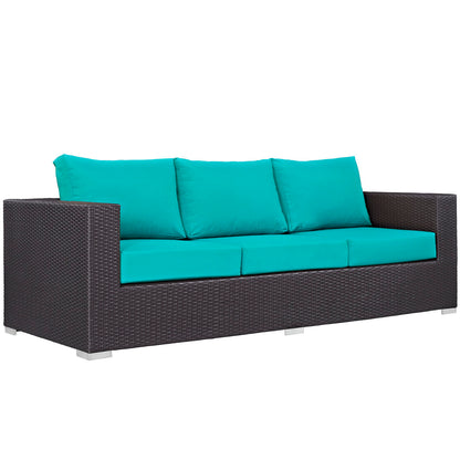 Dark brown wicker outdoor sofa with turquoise cushions and silver metal legs.