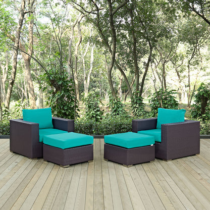 4-piece outdoor sectional set with turquoise cushions on a wooden deck, wicker seating with two armchairs & two ottomans, garden backdrop.