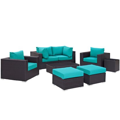 Dark brown wicker outdoor lounge set with turquoise cushions; includes sofa, two armchairs, two ottomans & coffee table.
