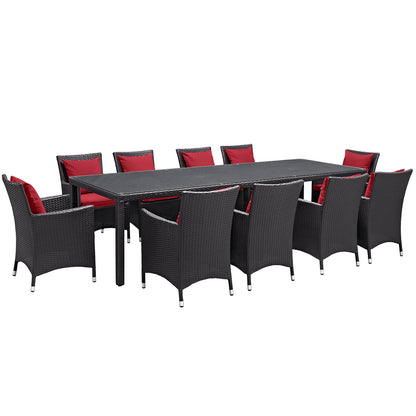 Outdoor espresso brown wicker dining set with red cushions, rectangular table and multiple chairs.