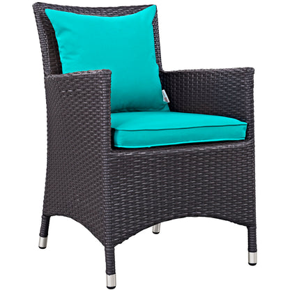 Dark brown wicker outdoor armchair with teal cushions and pillow, curved arms, metal-tipped legs.