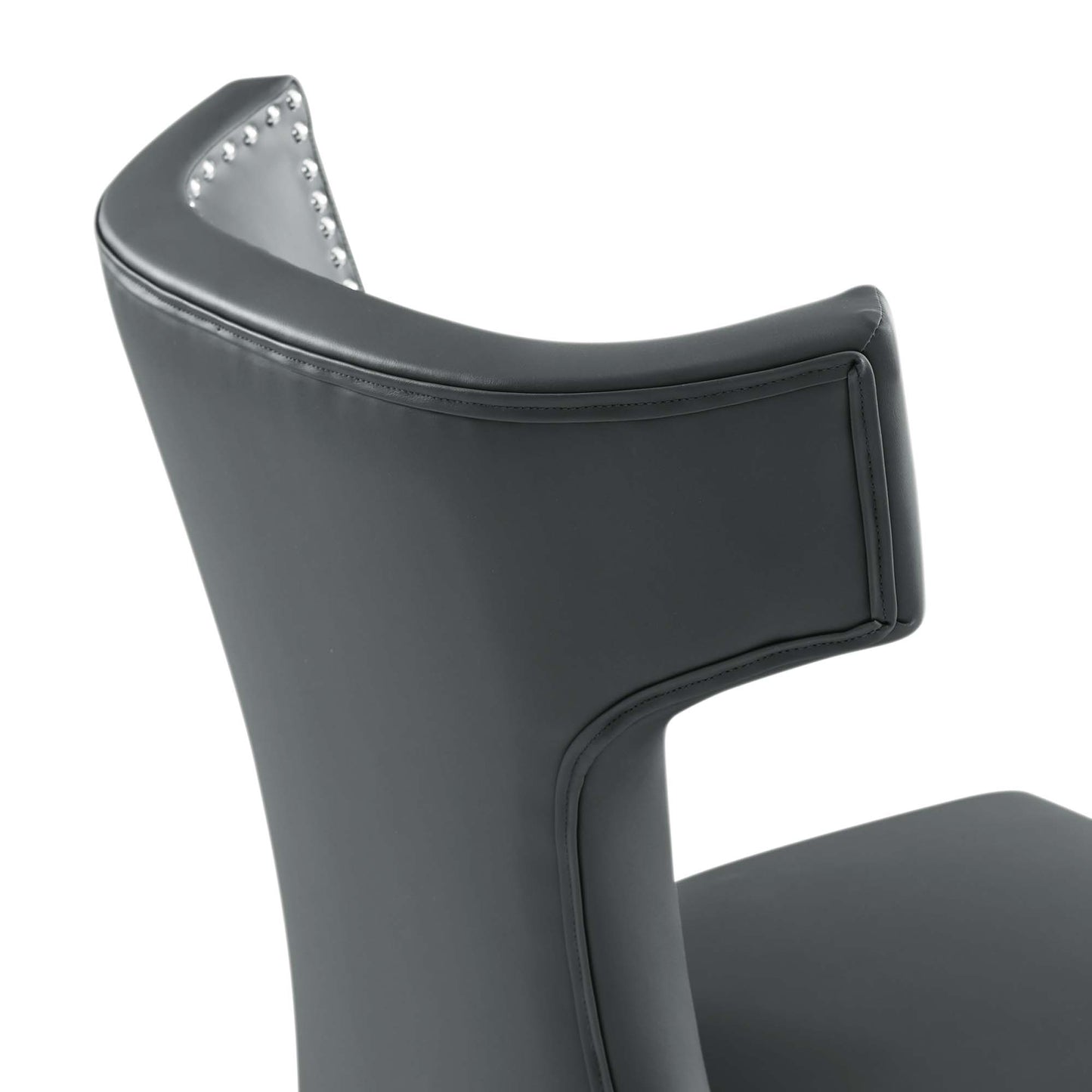 Dark gray vegan leather dining chair with curved back and nailhead trim along inner edge.