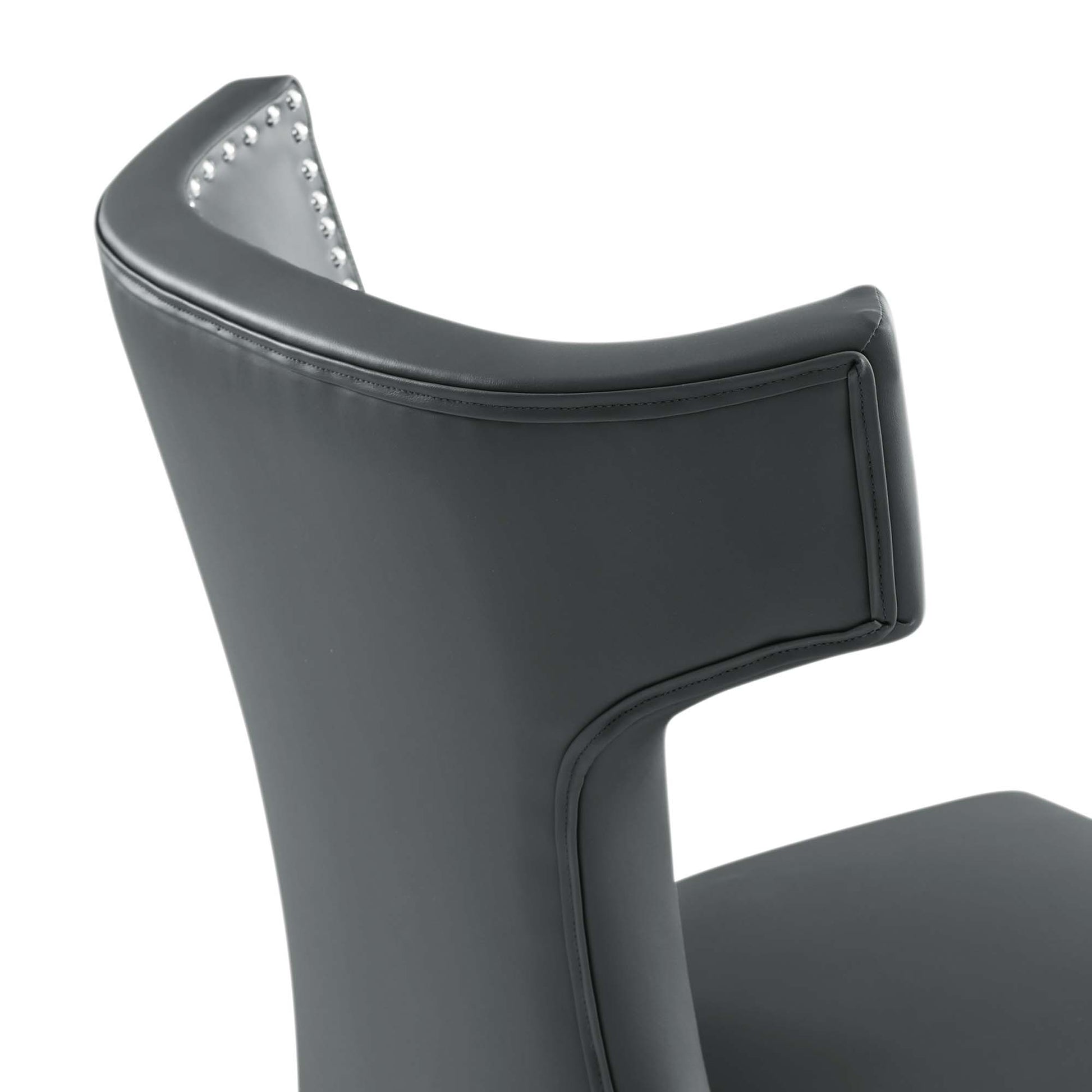 Dark gray vegan leather dining chair with curved back and nailhead trim along inner edge.