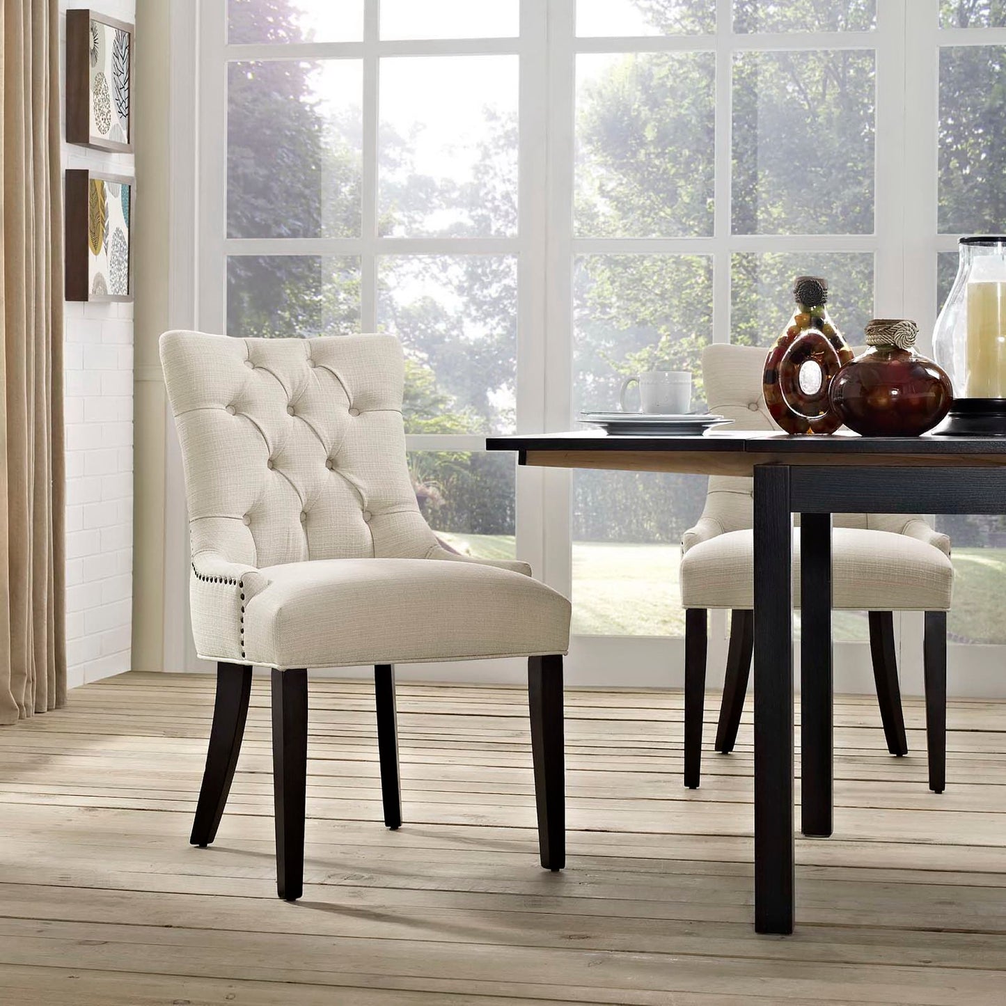 Beige tufted dining chair with dark wood legs beside a black-legged dining table in a bright, modern dining room.
