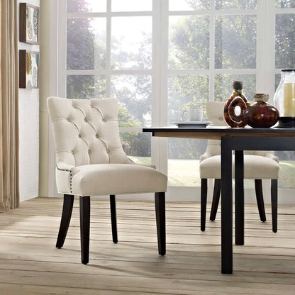 Beige tufted dining chair with dark wood legs beside a black-legged dining table in a bright, modern dining room.