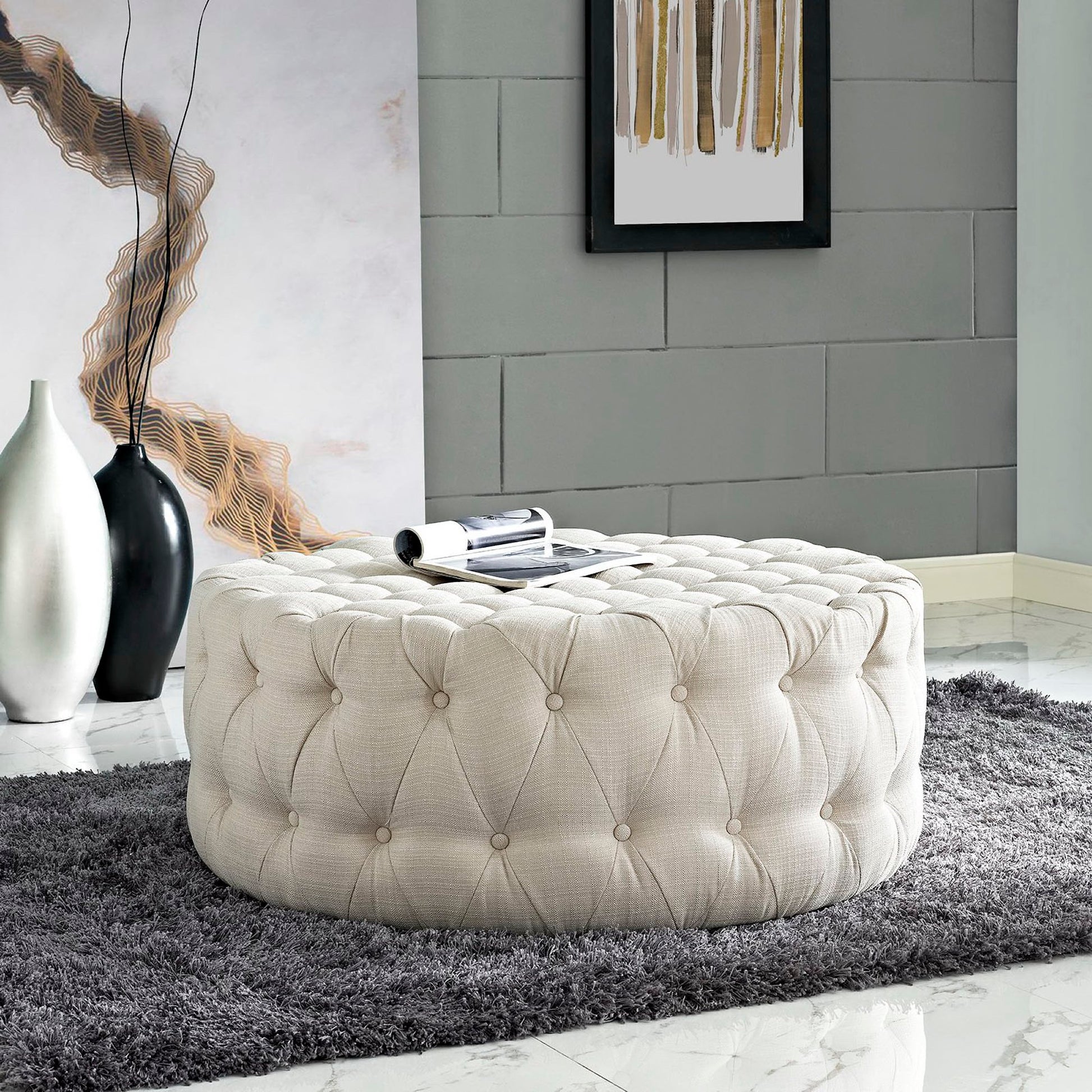 Brown round tufted fabric ottoman with button detail; sits on a dark gray shag rug in a modern living room.