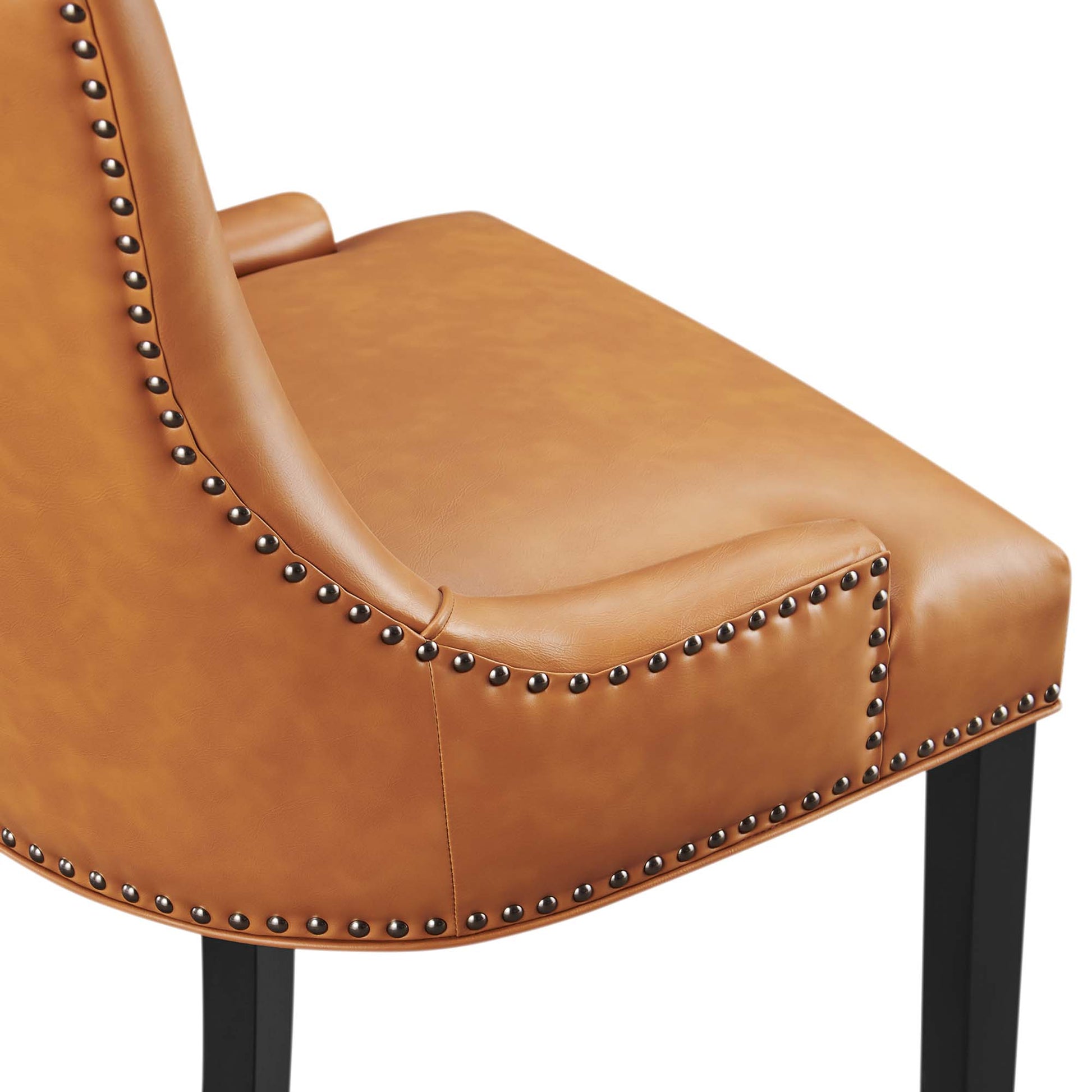 Tan vegan leather dining chair with nailhead trim along edges, curved back and seat, black legs