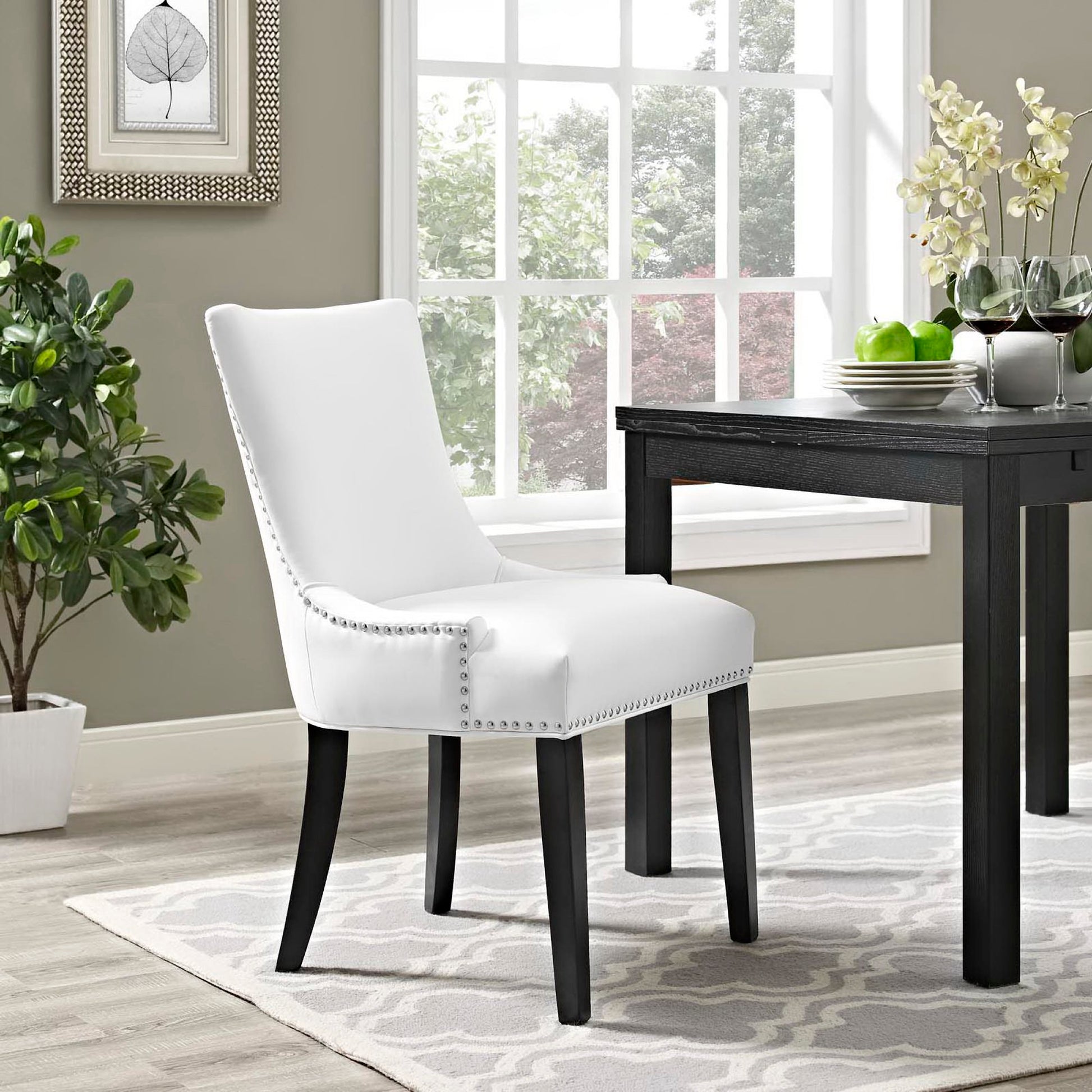 White vegan leather dining chair with silver nailhead trim & black legs, in a modern dining room.