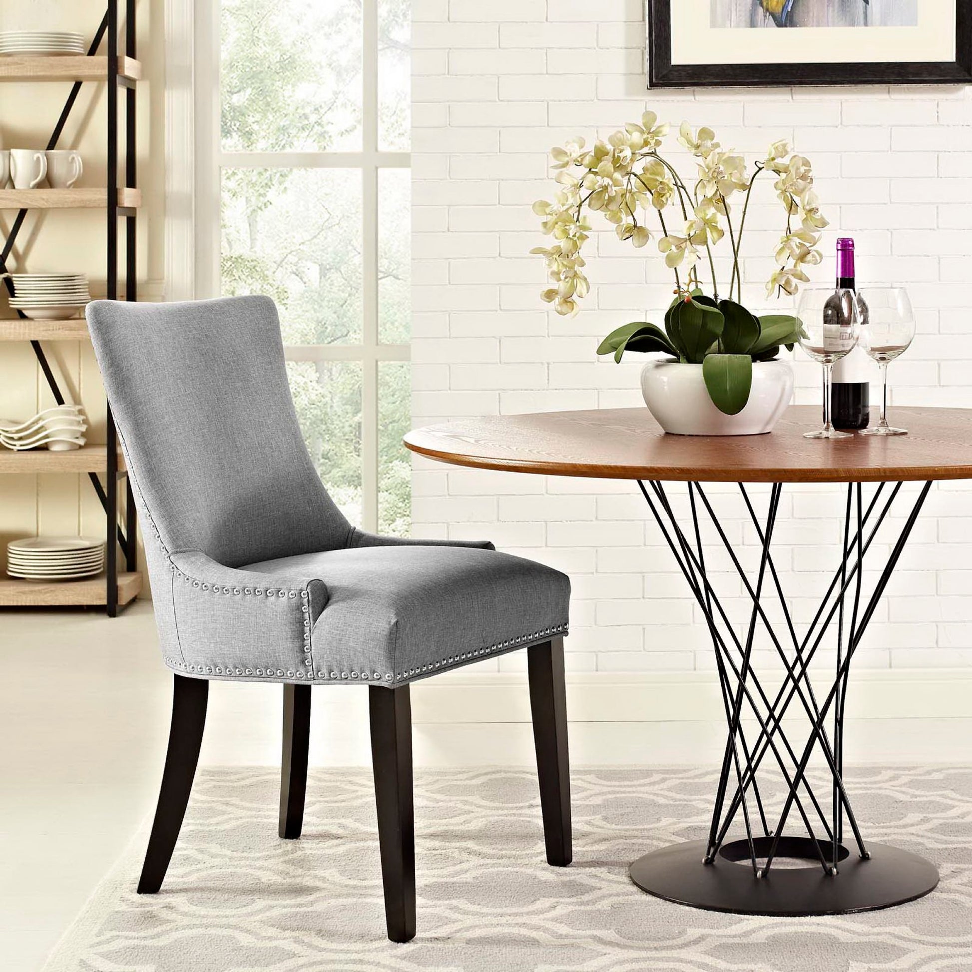 Grey upholstered dining chair with nailhead trim and dark wood legs.