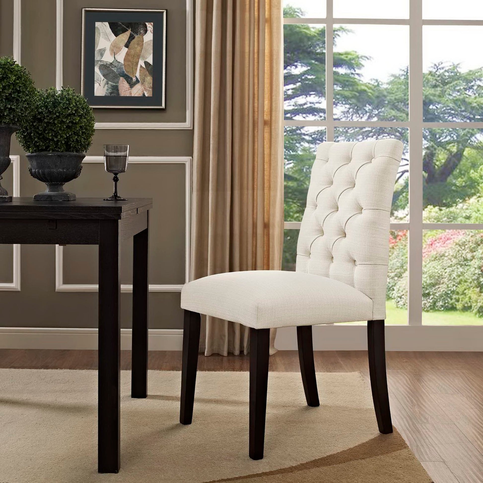 Brown button-tufted fabric dining chair with dark wood legs beside a dark table in a paneled room with a large window.