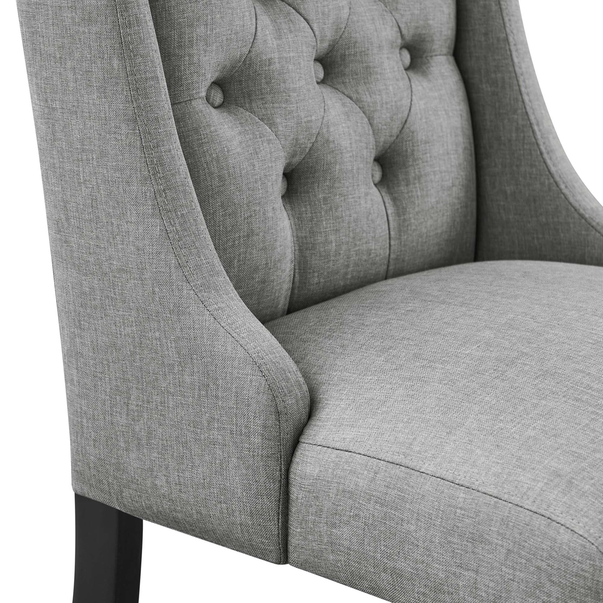 Light gray tufted fabric dining chair with curved arms and dark wooden legs.