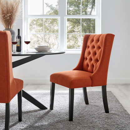Orange tufted dining chair with black legs beside a glass-top table in a bright modern dining room on a gray rug.