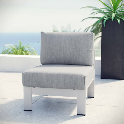 Armless outdoor aluminum chair with light gray cushions on a terrace with an ocean view