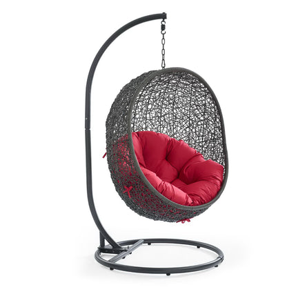 Gray woven egg chair with a red plush cushion, suspended from a curved metal stand.