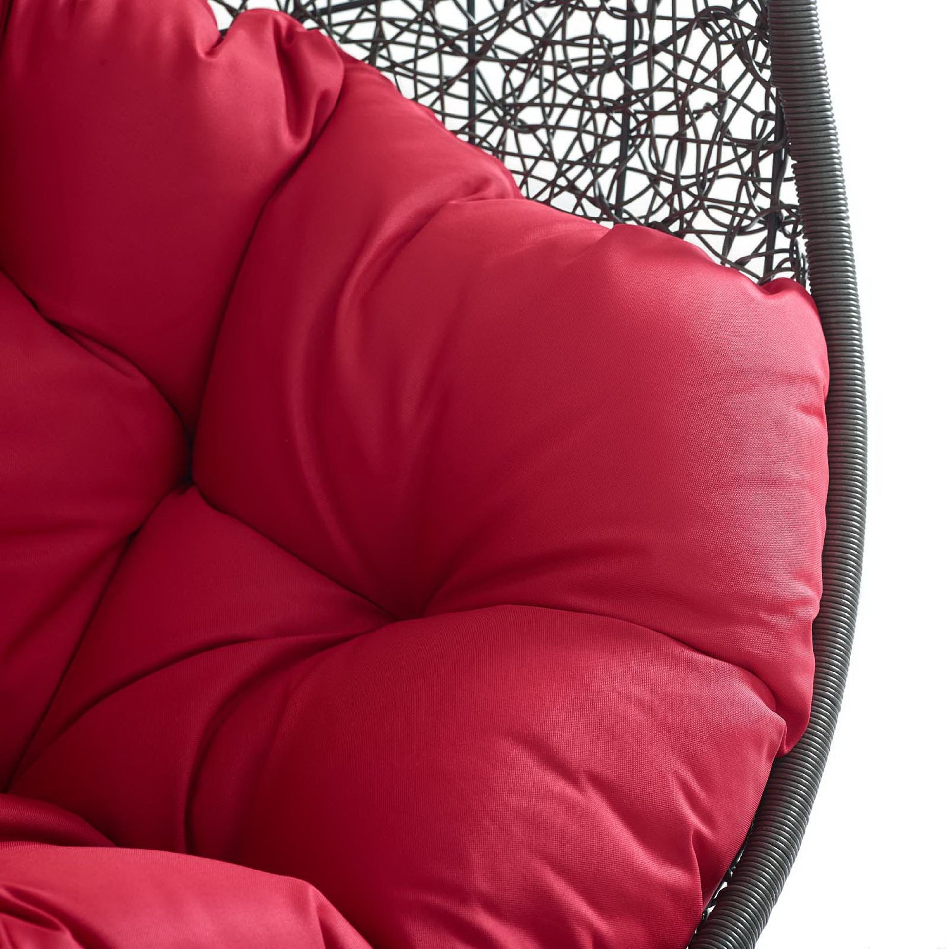Tufted red cushion on an outdoor patio swing chair with stand.
