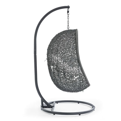 White woven half-sphere outdoor swing chair hanging from a curved metal stand for patio.
