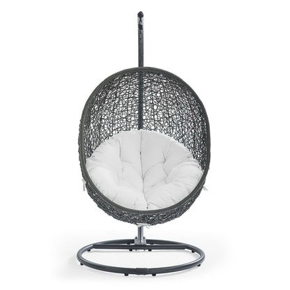 White woven hanging egg chair with plush white tufted cushion on a circular metal ring stand.