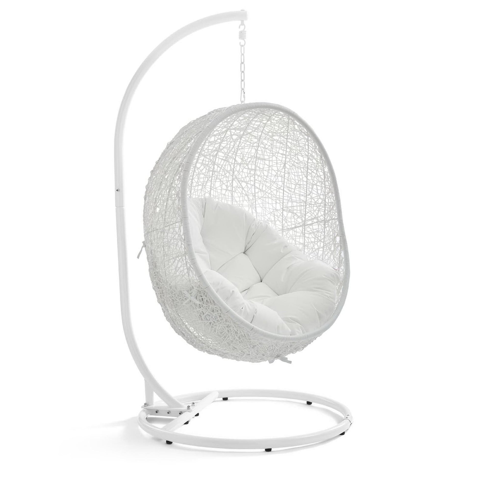 White hanging egg chair with woven rattan shell, plush white cushion & curved metal stand.