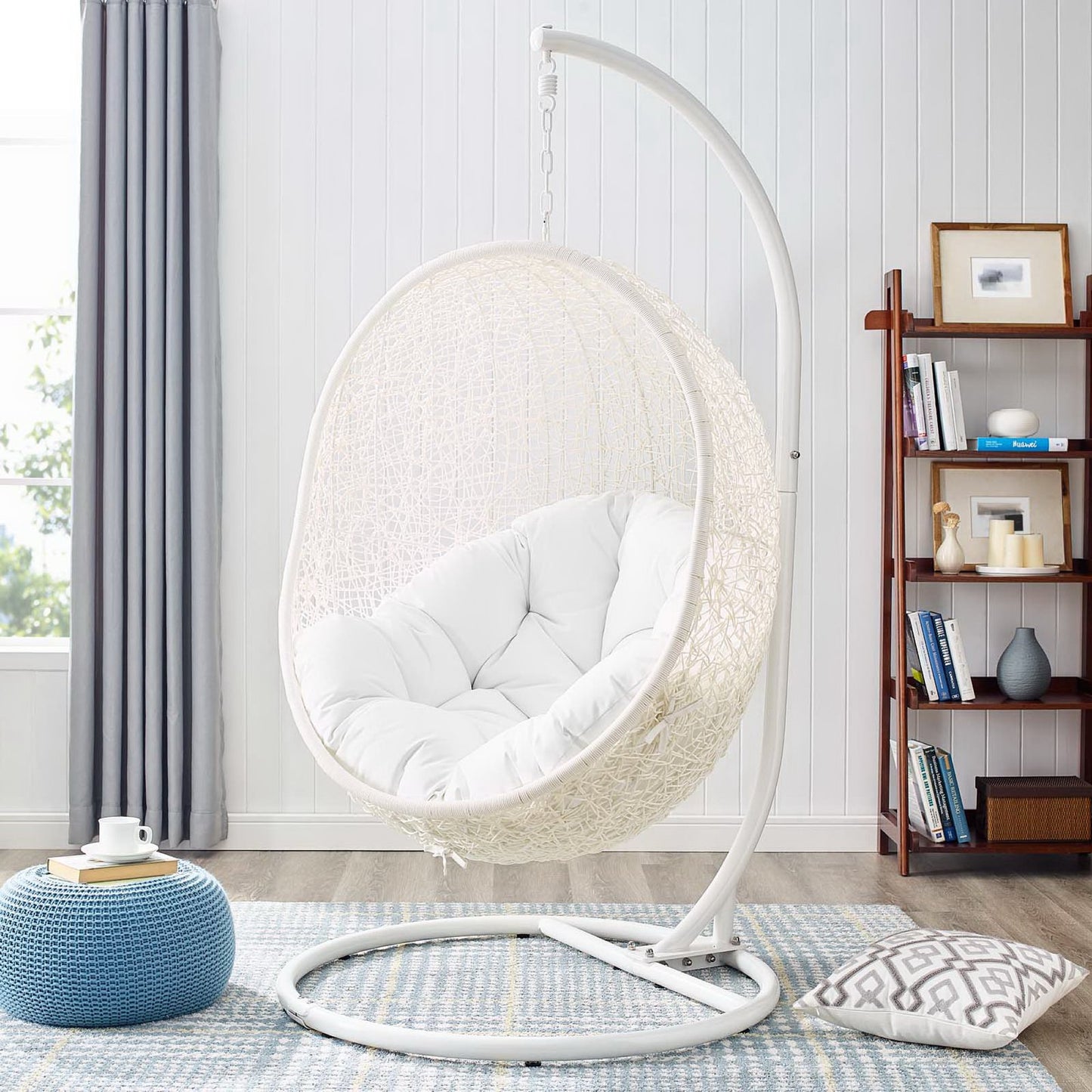 White woven outdoor patio swing chair with plush cushion on a curved metal stand.