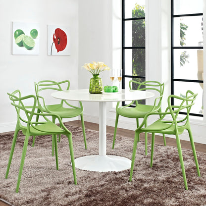 Lime-green modern dining chairs surround a white round pedestal table with a vase of flowers in a bright dining area.